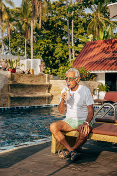 &Auml;ldre man dricker drink vid pool