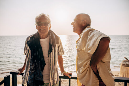 Leende &auml;ldre man st&aring;r i solnedg&aring;ng med partner