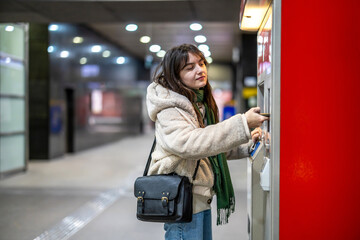 Young woman buying metro ticket from a machine
