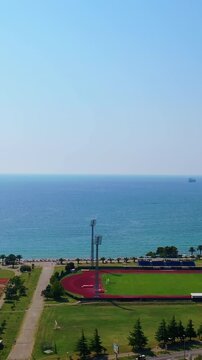 Approaching the beautiful waterscape of Adriatic Sea. Drone footage above the green area at the shore. Vertical video