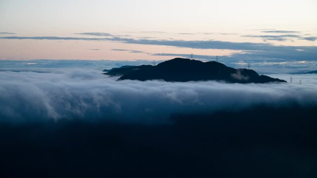 A tranquil spring morning at Lion's Head Mountain in Xindian, Taiwan, featuring an orange sky, moving white clouds, and silhouetted power towers.