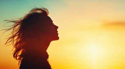 Silhouette of a woman against a colorful sunset background.
