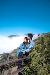 A couple is standing on a wooden bridge overlooking a mountain
