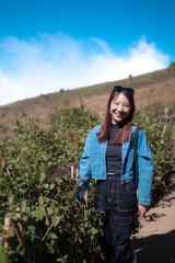 Naklejka premium A woman in a blue jacket and black pants stands in front of a field of plants
