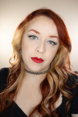 Fototapeta premium Model with red hair and some blonde highlights. Red lipstick and green eyes.