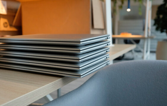 Stack of laptops on a table in a co-working space