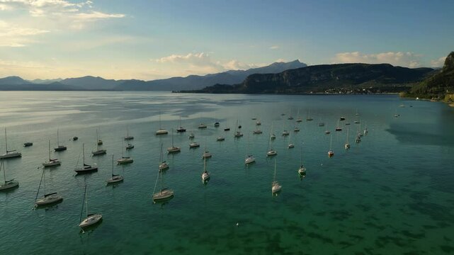 aerial scenic drone video of sailing boats arranged in a lines at Italian Garda Lake with clear transparent green water n sunny day 