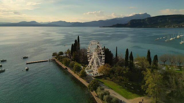 drone aerial video of an iron white ferris wheel  with scenic view to Italian Garda lake Bardolino in sunny day 