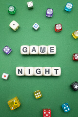 Word dice showing the phrase 'Game Night', with a selection of colourful dice around it on a vibrant green baize fabric..