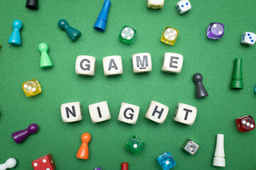 Word dice showing the phrase 'Game Night' with a selection of colourful dice and game tokens lying...