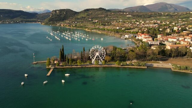 aerial drone panorama video of Bardolino at Italian Lago di Garda lake with ferries wheel, boats in sunny day 