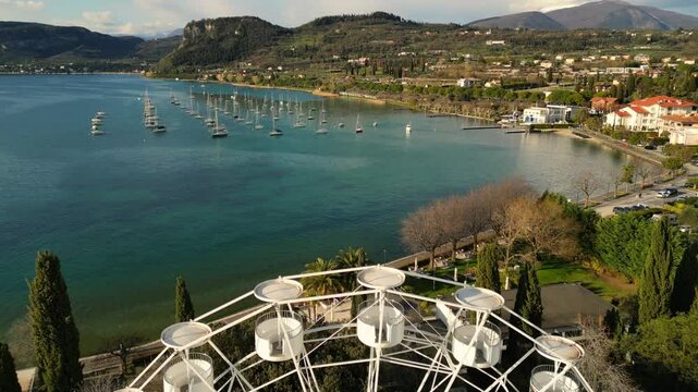 drone aerial video of an iron white ferris wheel  with scenic view to Italian Garda lake Bardolino in sunny day 