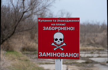 A red warning sign in Ukrainian stating that swimming and being on the beach is prohibited due to...