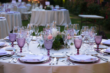 Elegant wedding reception setup with round tables, floral centerpieces and champagne glasses in a beautifully decorated venue.