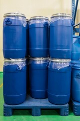 Closeup view of barrels stacked on top of each other. Blue plastic tanks on pallets in a chemical warehouse