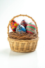 Wooden basket and nest filled with colorful decorated easter eggs isolated over white background. Concept of celebrating the easter holiday