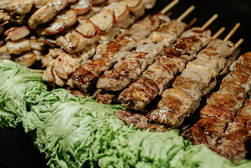A platter of grilled meat skewers, chicken skewers, and cheese, garnished with fresh lettuce, perfect for a BBQ or cookout, showcasing a colorful and delicious variety of grilled food.