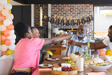 Adult family celebrating retirement with joyful toast around dining table at home