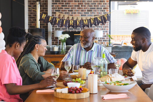 Adult family celebrating retirement with dinner, sharing laughter and wine at home