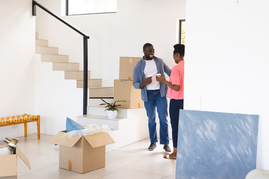 African American couple unpacking boxes in new home, smiling and enjoying fresh start together