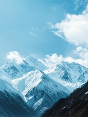 Obraz premium Majestic Mountain Panorama: A breathtaking view of snow-capped mountain peaks reaching towards a vibrant blue sky, adorned with fluffy clouds, offering a serene and awe-inspiring panorama.