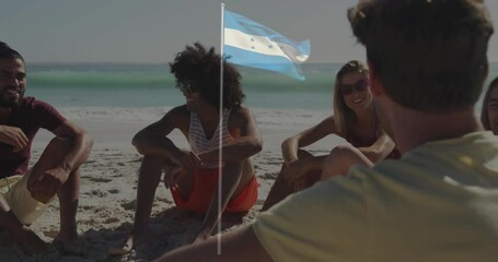 Relaxing on beach, group of friends with Honduras flag waving behind them - Powered by Adobe