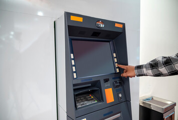 The male hand chooses the option button on an ATM (Automatic cash machine) to access bank service or withdraw money. Concept of technology, finance, and banking