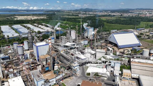 Vis&atilde;o a&eacute;rea de uma planta industrial de produ&ccedil;&atilde;o de papel, com destaque para chamin&eacute;s e caldeiras. A imagem ilustra o processo industrial e a infraestrutura de uma f&aacute;brica de papel em opera&ccedil;&atilde;o