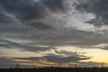 spring beautiful sunset sky with layers of clouds and yellow highlights from yellow sunset