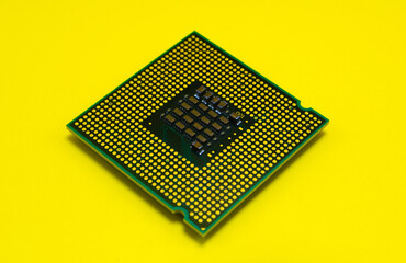 The intricate heart of modern technology, a microchip's golden pathways against a vibrant yellow backdrop.
