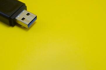 Fototapeta premium A sleek black USB drive rests against a vibrant yellow backdrop, a simple yet striking contrast symbolizing modern technology and bold design.