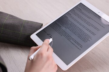 Electronic signature. Woman using stylus and tablet at wooden table, closeup