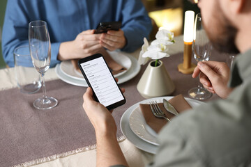 Couple choosing dishes from digital menu at restaurant, closeup