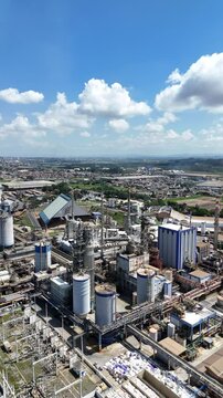 Vis&atilde;o a&eacute;rea vertical de uma ind&uacute;stria de papel e celulose, mostrando a estrutura fabril com caldeiras, chamin&eacute;s e equipamentos em opera&ccedil;&atilde;o. A imagem destaca o processo produtivo industrial