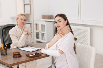 Injured woman and lawyer in office, selective focus