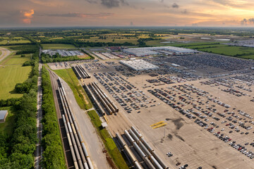 Automotive industry. Import or export of new cars by rail. Train auto racks at production factory warehouse. Vehicles for sale at logistics business parking lot