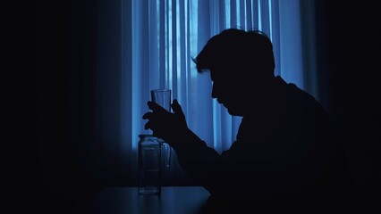 Silhouette of a Man Holding a Glass in Blue Light