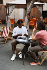 Joyful gay couple shares intimate moments over coffee at a cozy cafe in the afternoon sun