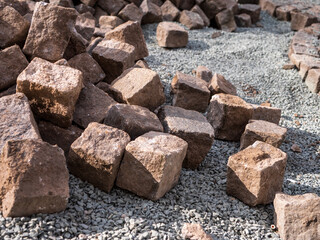 Close-up of granite cobblestones on gravel, prepared for pavement construction in an outdoor setting.