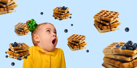 Excited girl, child in yellow shirt with green bun staring up at floating waffles and blueberries...