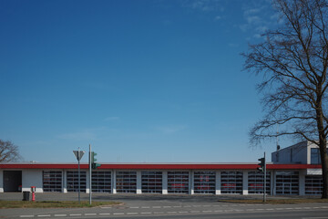 Obraz premium A low, modern fire station building with a row of large, glass-panel garage doors.