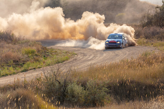 Rally Car on a Turn and a Cloud of Dust in the Sunlight