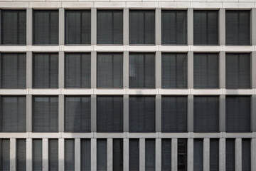 Obraz premium A contemporary architectural facade featuring a grid layout of rectangular windows with closed horizontal blinds.