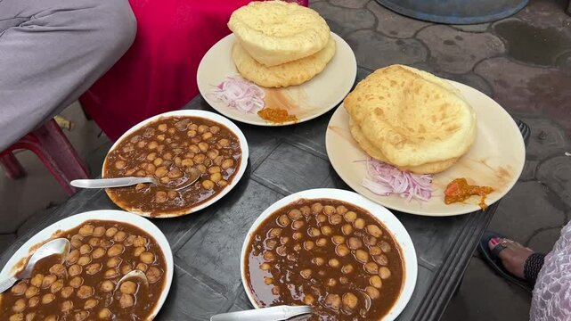 Group of people having spicy chana bhatura from a road side stall in India.