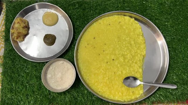 Home made khichri with alu bharta and chutney in a green background