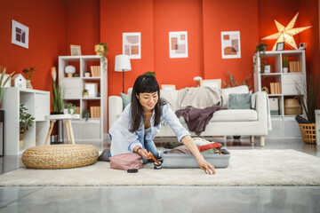 japanese woman sit on floor and pack her suitcase baggage for trip