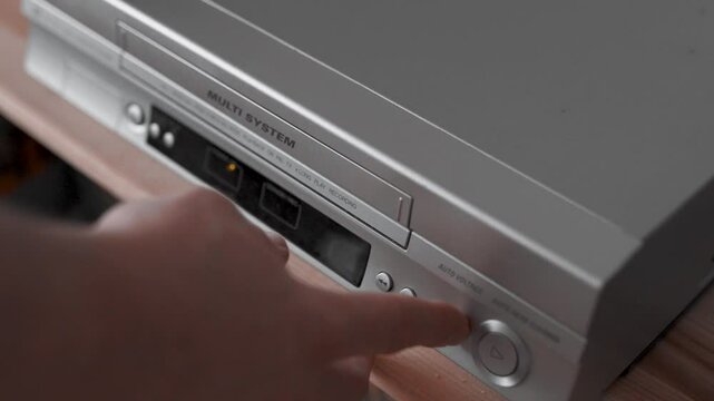 Close up of a hand puting a videotape into video player. Retro vhs cassete in a player.
