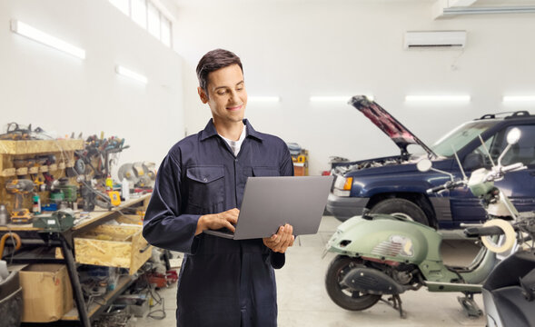 Auto mechanic using a laptop computer in a car garage