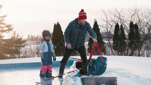 Dad and girl playing hockey outdoors