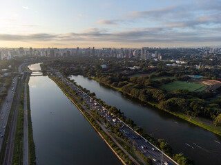 Obraz premium Rising sun on a river within the metropolis of São Paulo with the Pinheiros riverside.